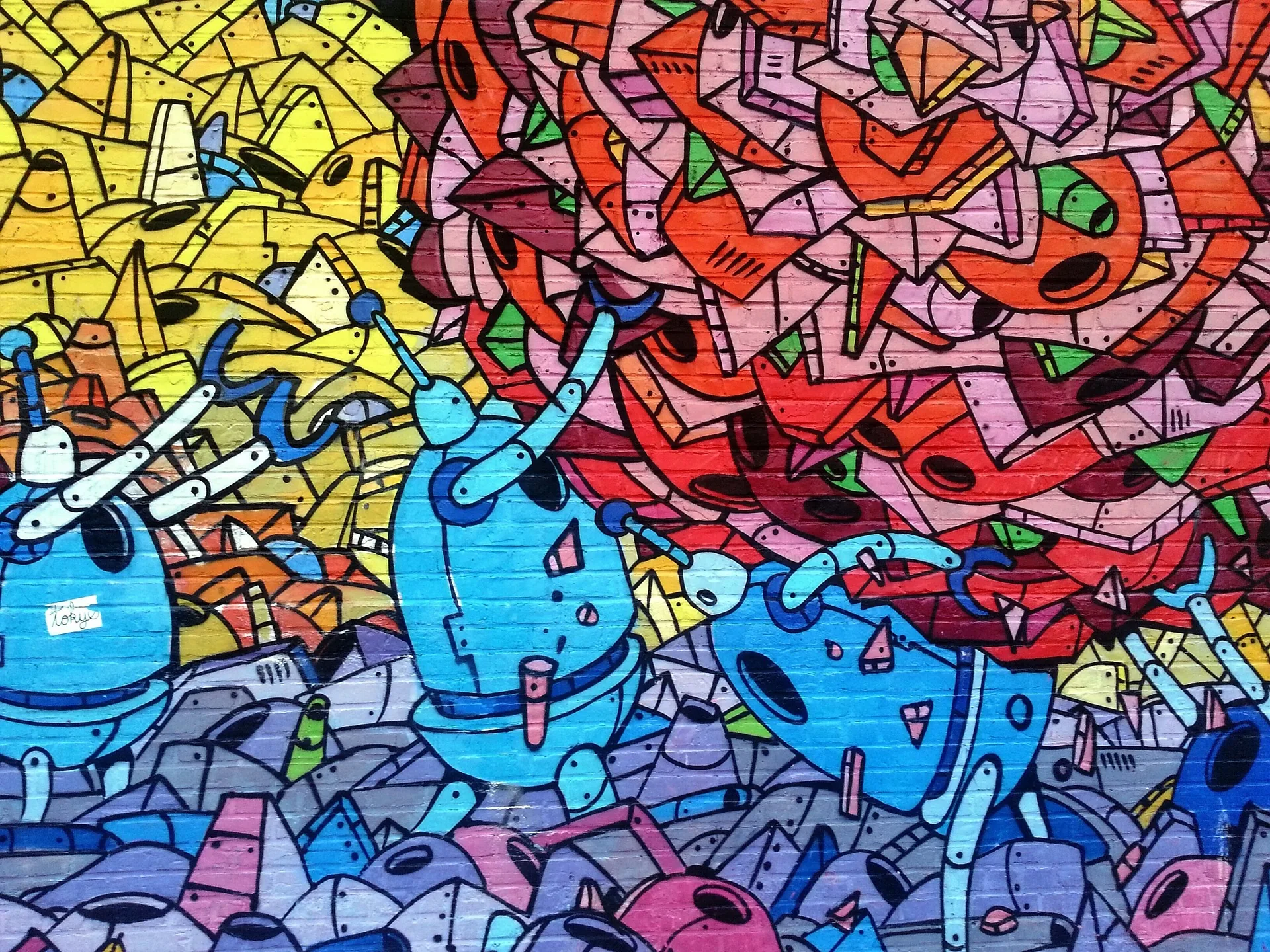 Farbenfrohes Graffiti mit abstrakten Figuren und Schriftzügen auf einer Backsteinwand