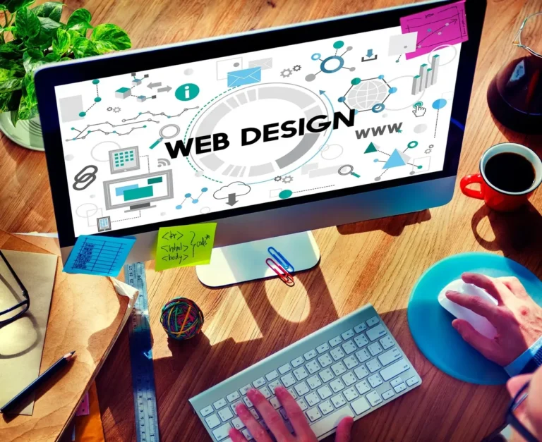 Monitor mit Webdesign-Grafik, HTML-Code und Arbeitsmaterialien auf einem Schreibtisch