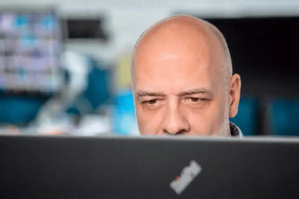 Konzentrierter Mann blickt während der Arbeit auf einen Laptop im Büro